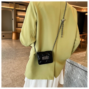 Quilted black chain crossbody bag worn by a model in a formal suit for a stylish look