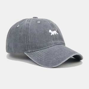 Dettaglio del cappello da baseball in denim lavato con ricamo di cane bianco e cuciture