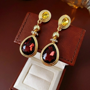 Close-up of vintage gold earrings with red pear-shaped gemstones in a brown leather box