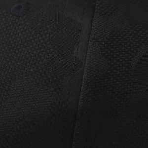 Macro shot of black jacquard fabric with woven floral patterns on a baseball cap top