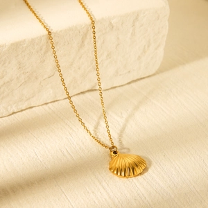 Elegant gold stainless steel necklace with a detailed scallop shell pendant on stone
