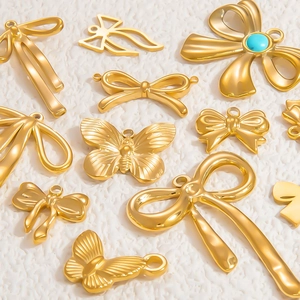 Polished 18k gold stainless steel butterfly and bow charms on white plush background