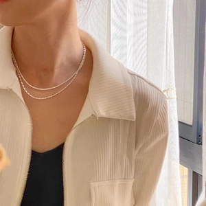 Double-layered minimalist silver necklace with bead and twisted chains on female model
