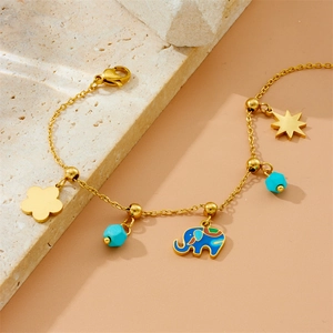 Bracelet doré avec breloques éléphant et perles bleues sur un support en pierre