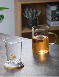 Detail view of transparent glass tea cup with mountain base and wooden coaster set