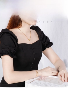 Close-up of gold heart and fish tail necklace set worn by model with elegant black dress