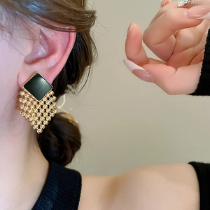 Detailed view of woven diamond tassel earrings with black square and gold bead fringe