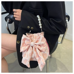 Detailed shot of pink bow handbag featuring a pearl handle and textured floral jacquard fabric