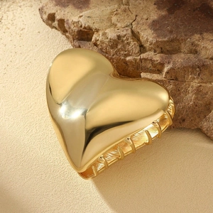 Elegant gold metal heart-shaped hair claw clip on stone background for women