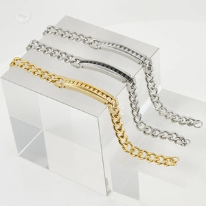 Detailed view of gold, silver, and black stainless steel Cuban link bracelets on acrylic