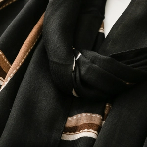 Close-up of black cotton-linen scarf with brown and white stripes in a soft knot