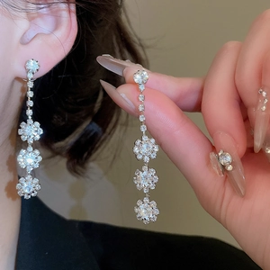 Close-up of elegant silver flower tassel earrings with crystals on a model