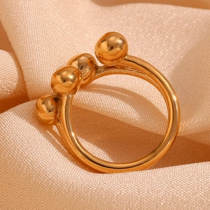 Detailed macro view of 18K gold plated open ring with three spheres on beige fabric