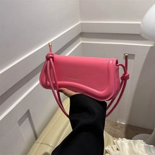 Dettaglio mini borsa a tracolla rosa con design curvo e spalline con nodi