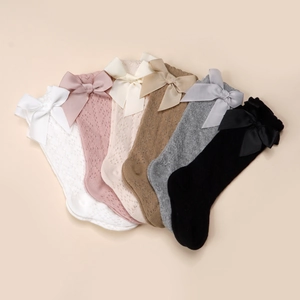 Détail de chaussettes hautes en maille ajourée pour bébé avec de grands nœuds colorés