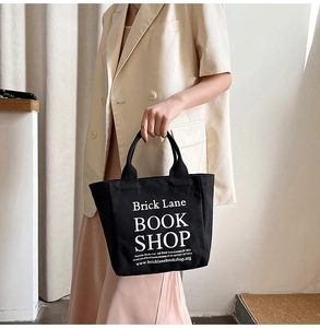 Close-up of black canvas tote bag with Brick Lane Bookshop print held by a model