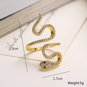 Detailed macro view of gold-plated snake ring with white zircons and green gem eyes