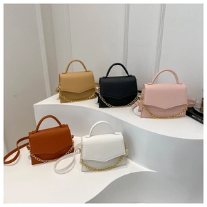 Detail view of small square crossbody bags with chain decor in five colors on a white stand