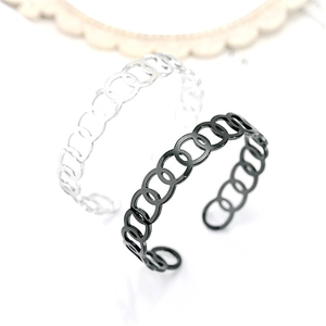 Close-up of two open titanium steel cuff bracelets with linked circle design in silver and black.