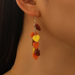 Close-up of dangling autumn maple leaf earrings with multi-layered orange and yellow petals