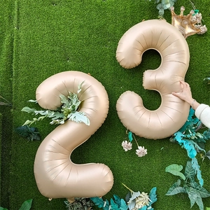 Detail of cream matte number balloons 2 and 3 with gold crown on green grass background