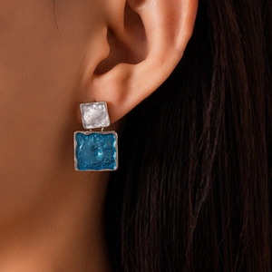 Macro view of geometric square earrings with sea blue wave texture and silver metal details