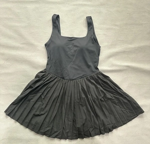 Detail view of black tennis dress with pleated skirt and square neckline