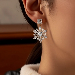 Close-up of 14k gold plated snowflake drop earrings with marquise-cut zircons