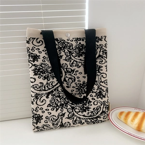 Detail of black and white paisley knit tote bag with black strap and silver snap button