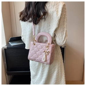 Detail of pink quilted handbag with heart stitching and pearl bow charm accessory