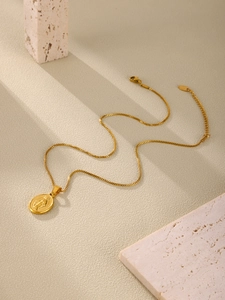 Macro detail of golden box chain and religious Virgin Mary pendant on marble base