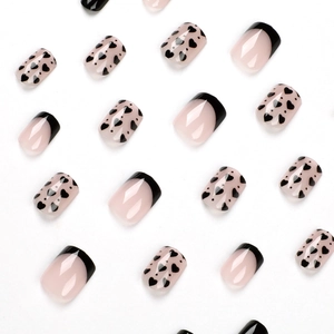 French tip press-on nails with black heart patterns and pink base on white background