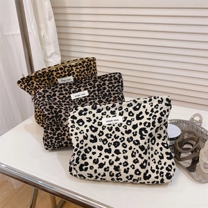 Detailed view of three leopard print canvas cosmetic bags with metal zippers and brand labels