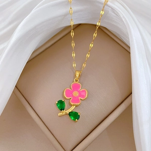 Collier élégant en titane doré avec fleur en émail rose et feuilles en gemmes vertes sur soie