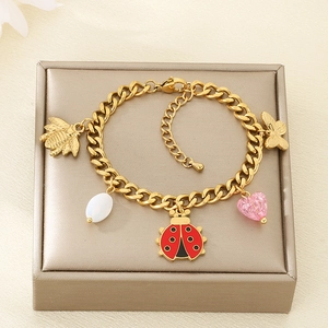 Close-up of gold chain bracelet featuring ladybug, bee, butterfly and crystal charms