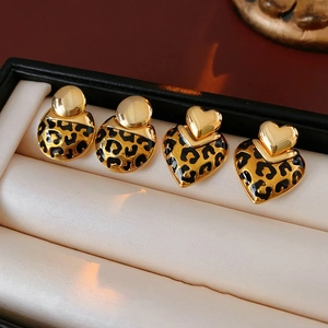 Leopard print gold plated heart and round stud earrings on beige satin jewelry pillow