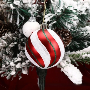 Detail of red and white spiral Christmas ball with green glitter on a snowy tree branch