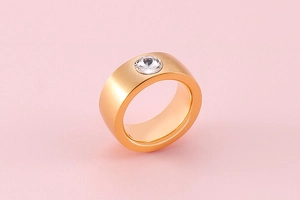 Detail view of rose gold stainless steel wide ring with brushed finish and zircon inlay