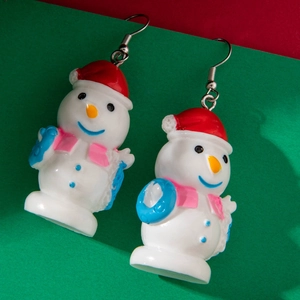 Detailed view of snowman stud earrings with red hat and blue scarf on festive background