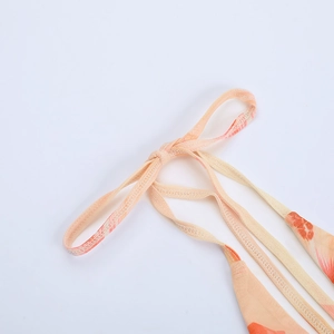 Close-up of orange floral print on mesh fabric with fine adjustable shoulder straps