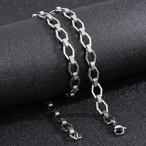 Close-up of silver geometric chain necklace with Greek key pattern on black surface