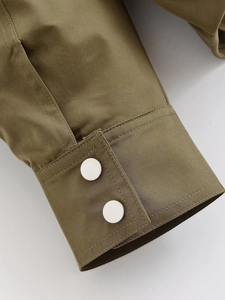 Detail of olive green bomber jacket cuff with silver matte metal buckle buttons