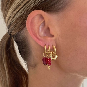 Close-up of gold hoop earrings set with red heart and bead charms on model