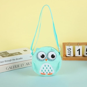 Close-up of cute mint green owl plush crossbody bag with glitter eyes on a soft desktop