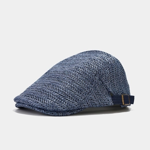 Detailed macro view of the blue straw beret cap with metal buckle and woven texture