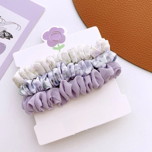 Lot de trois chouchous en tissu à fleurs et violets sur une carte de présentation