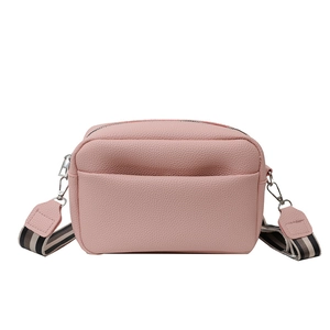 Pink lychee leather crossbody bag with striped canvas strap on a white background