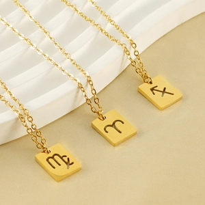 Detailed close-up of hollow square zodiac pendants in gold finish on a minimalist display