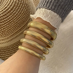 Detail of four gold tubogas style stretch bracelets worn on wrist for elegant styling