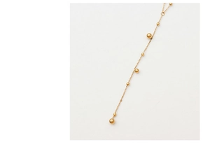 Close-up of golden beaded long tassel chain necklace made of durable titanium steel